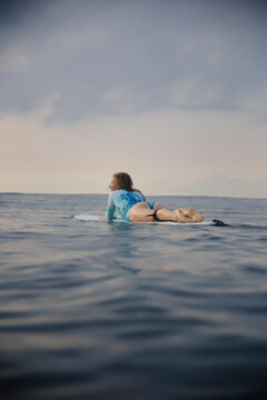 Full length of carefree woman lying on surfboard in sea against sky