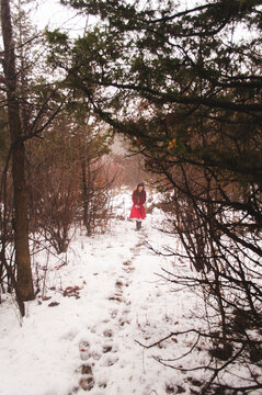Girl walking on snowy field amidst forest