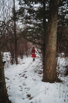 Mid distance view of girl walking on snowy field amidst forest