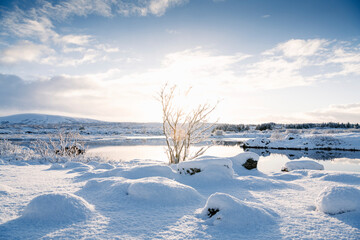 Lake amidst snow covered field against cloudy sky