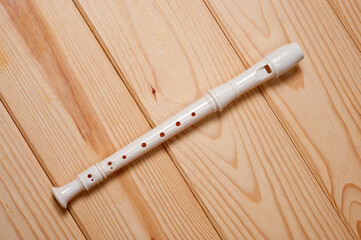 Block flute wind musical instrument photographed on a wooden surface.