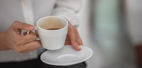 Banner of Asian woman Proprietor holding hot coffee in white ceramic cup to sniff smell of espresso in office work place . business owner entrepreneur girl carry coffee break to sniff fragrant smell