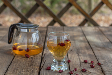 Red tea in a transparent cup on a wooden table, rosehip tea, rustic