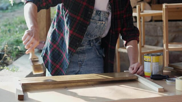 Close-up slow motion footage of a person using a brush to varnish a wooden board.