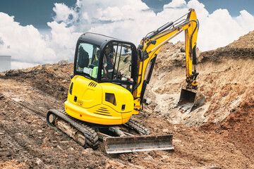 Mini excavator at the construction site. Compact construction equipment for earthworks. An...