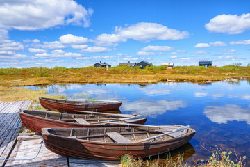Idyllic landscape view with row boats at a mountain huts jetty - obrazy, fototapety, plakaty