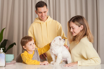 Adorable parents with child son and white dog, three abstract plastic bottles on the table