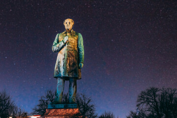 Fototapeta na wymiar Colourful Night Starry Sky In Blue Colors. Helsinki, Finland. Close Up Of Statue Of Johan Ludvig Runeberg On Esplanadi Park In Lighting At Night Illumination. National Poet And Lyric Of Finland.