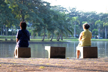 two old woman, senior sitting on a bench in the park