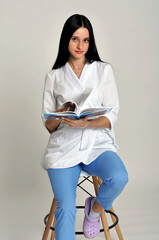 Fototapeta premium girl doctor in a white coat and medical gloves posing