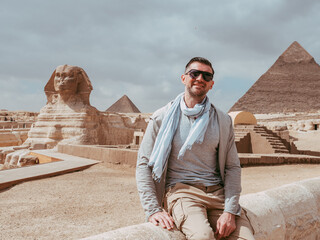 Stylish man against the background of the Giza pyramids complex. Clear, sunny day, blue sky....