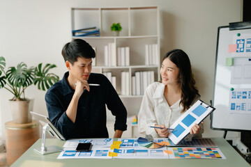  UX developer and ui designer brainstorming about mobile app interface wireframe design with customer breif and color code at office..