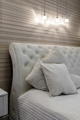 Bright bedroom with large white bed and capitone headboard