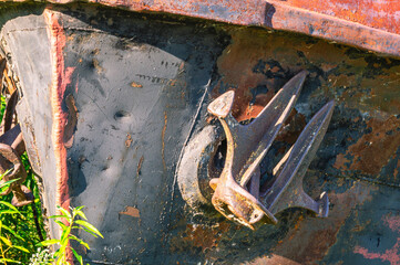 Old rusty ships lie on the riverbank. The river bank and rusting ships. A rusty anchor on an old...