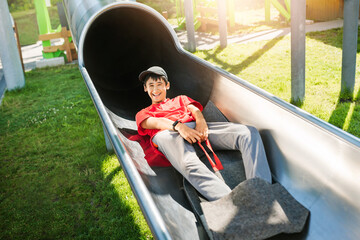 Child slides down metal chute in an adventure amusement park.