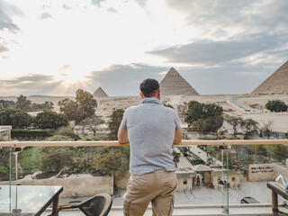 Stylish man against the background of the Giza pyramids complex. Clear, sunny day, blue sky....
