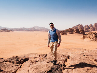 Fototapeta premium Stylish man and the sights of the Wadi Rum desert in Jordan. Clear, sunny day. Vacation and travel concept