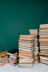 Fototapeta premium many books stacked on a table on a green background in the science knowledge library