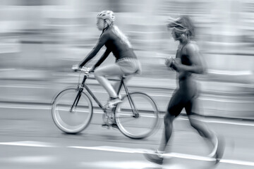 cyclists and runner on city street in monochrome tonality