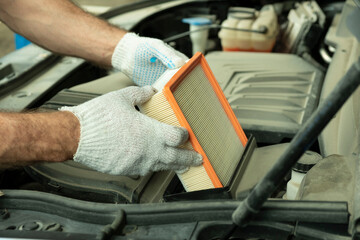 Car maintenance at a car service. An auto mechanic replaces the engine's air filter. Installing a new air filter. Close-up.