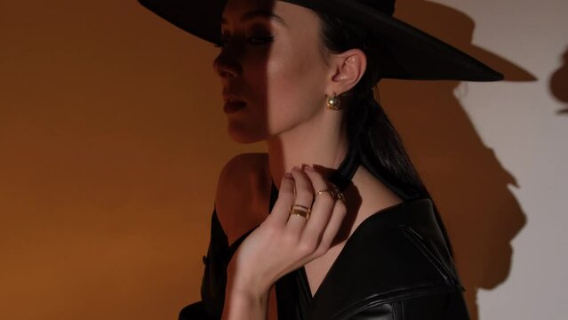 Fashion portrait of a girl in the studio with a black hat with golden decorations. Jewelry