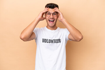 Young volunteer caucasian man isolated on beige background with surprise expression