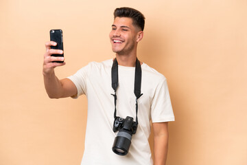 Young photographer caucasian man isolated on beige background making a selfie