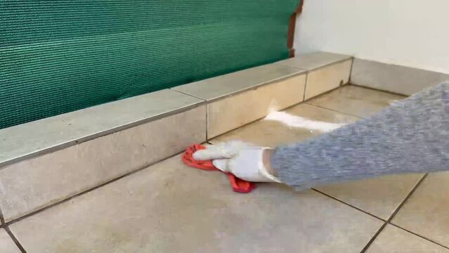 female hands wipe the dust after grouting ceramic tiles with a rag. A worker wipes the tiles with a rag after laying the tiles on the wall.