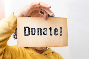 Child hand holding a piece of paper with the word Donate