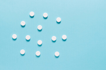 Medicine pills on a blue. Close up of white round pills with pharmacy and medical concept.  Flat lay, top view. 