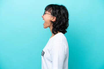 Young volunteer Argentinian woman isolated on blue background laughing in lateral position