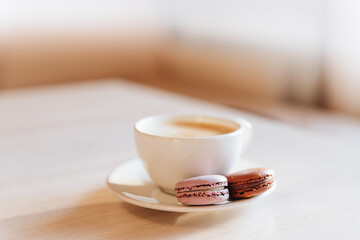A cup of cappuccino coffee, macaroni cakes, on a table.concept of freshness and pleasant coolness on a hot day. caramel macaroons. Light flatley with dessert.exquisite dessert