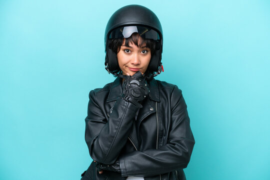 Young Argentinian woman with a motorcycle helmet isolated on blue background thinking