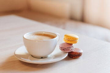 A cup of cappuccino coffee, macaroni cakes, on a table.concept of freshness and pleasant coolness on a hot day. caramel macaroons. Light flatley with dessert.exquisite dessert