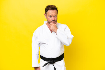 Middle age caucasian man doing karate isolated on yellow background thinking © luismolinero