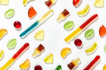 Chewing marmalade of different shapes, tastes and colors lie in a pattern on a white background.  Free space in the center