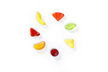 Gummy candies in the form of fruits and berries lies in a circle on a white background.