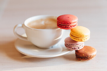 A cup of cappuccino coffee, macaroni cakes, on a table.concept of freshness and pleasant coolness on a hot day. caramel macaroons. Light flatley with dessert.exquisite dessert