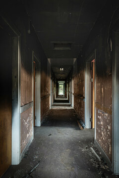 Abandoned derelict Hospital corridor, with peeling paint and black water stains on the walls from water damage.