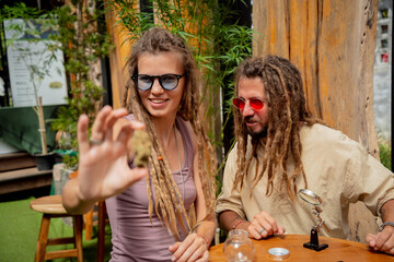 Hippie style couple examines joints and buds of medical marijuana.