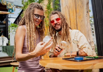 Obraz na płótnie Canvas Hippie style couple examines joints and buds of medical marijuana.