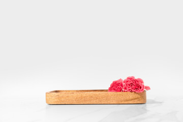 Cosmetics product presentation scene made with wooden tray pedestal and pink roses on white...