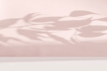 Abstract light pink background. The shadow of tropical plant leaves on a paper wall.