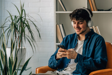 young man at home with mobile phone and headphones
