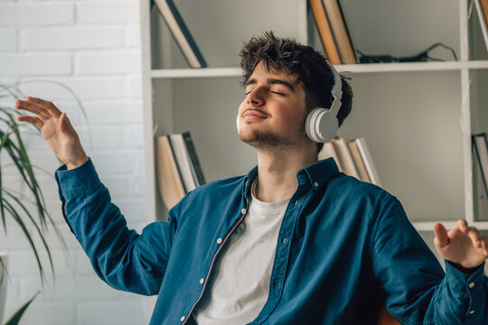 young man at home enjoying listening to music with headphones