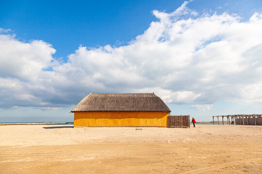 Empty beach with a thatched roof hut and the sea in early spring on a sunny day.