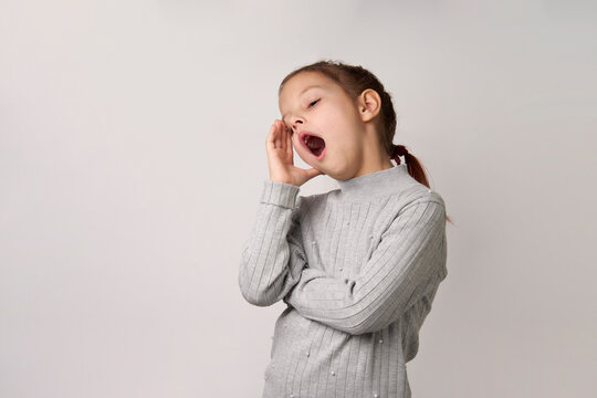 Tired child girl yawning, open mouth, white background - Powered by Adobe