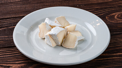 Pieces of camembert or brie cheese in a ceramic plate.
