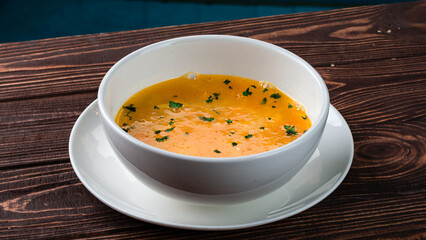 Pumpkin cream soup with greens in a bowl.