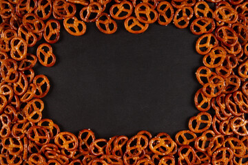 Rectangular frame of mini pretzels on black background. Dark backdrop with Crunchy twists